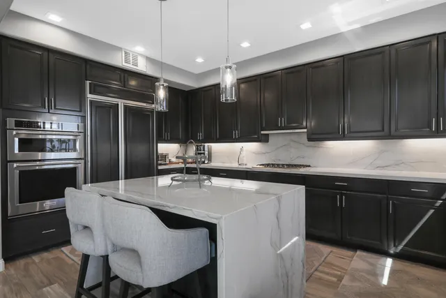 a kitchen with kitchen island granite countertop a sink cabinets and stainless steel appliances