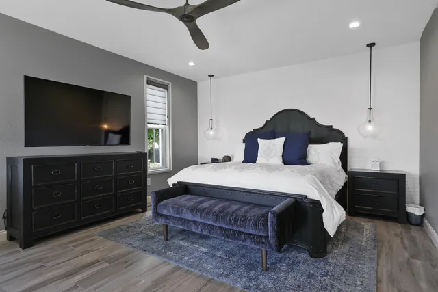 a bedroom with a bed and a flat tv screen on dresser