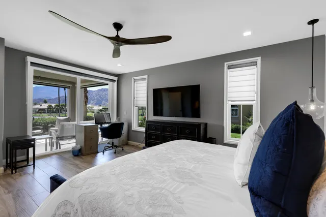 a spacious bedroom with a bed and a flat tv screen on dresser