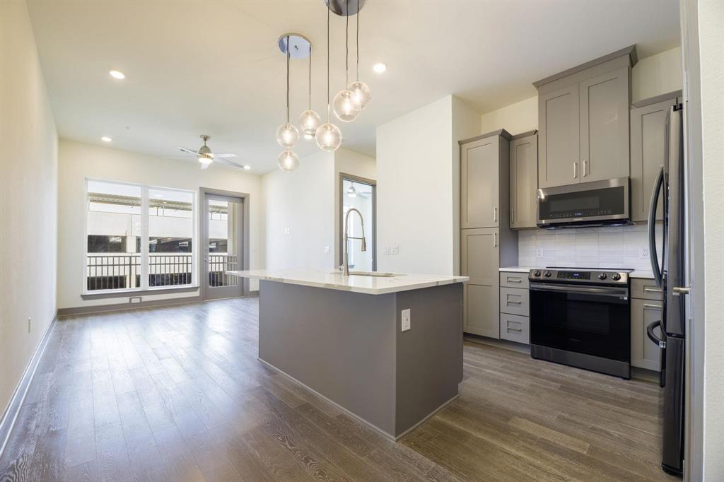 2700 Old Denton Road, Unit 3362 Carrollton, TX 75007 - Photo 2 of 18 a large kitchen with stainless steel appliances granite countertop a stove and a wooden floors