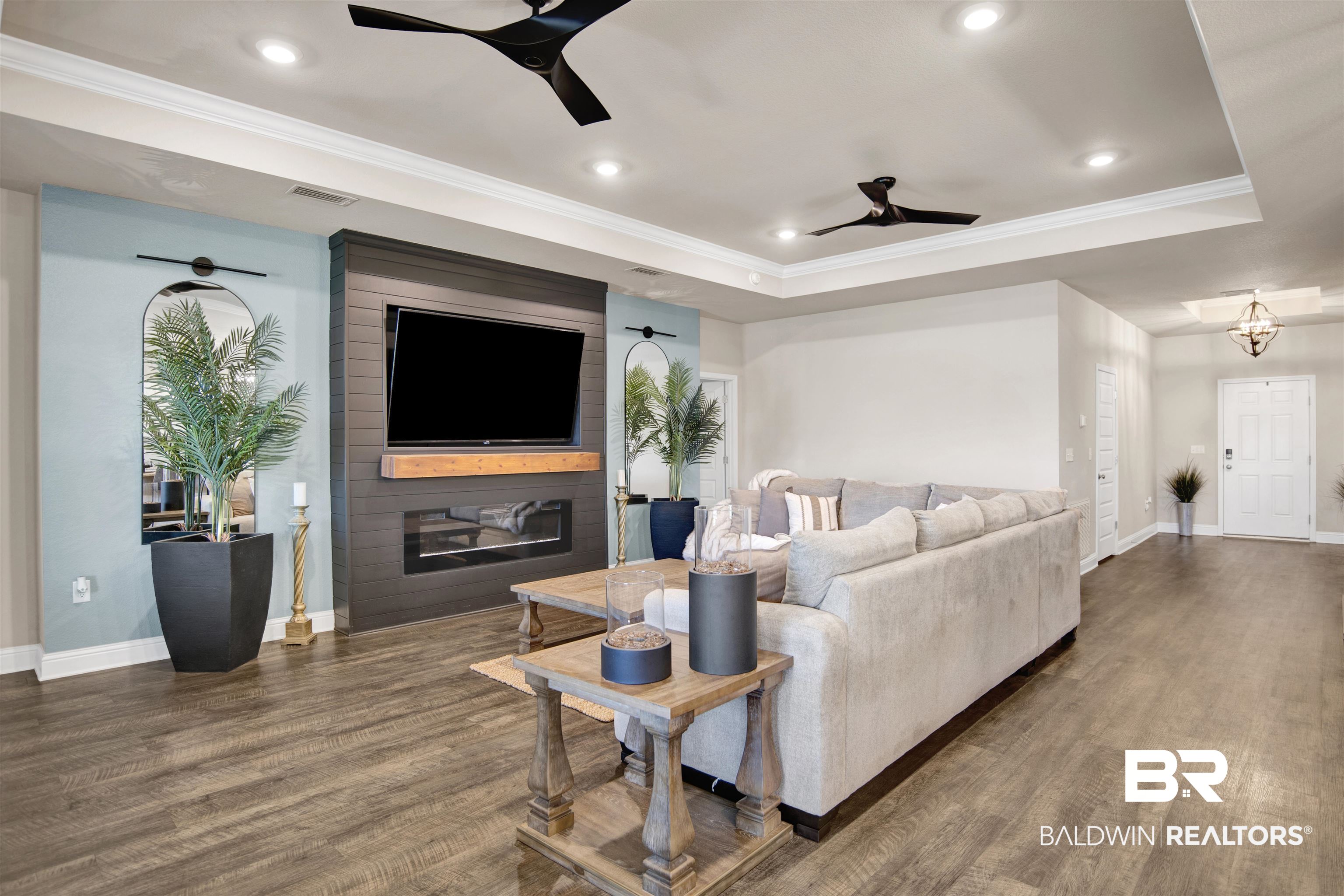 8493 Bronze Lane Foley, AL 36535 - Photo 5 of 38 Living area featuring wood-finish flooring, a tray ceiling with recessed lighting and two ceiling fans, and a built-in fireplace with a wooden mantel