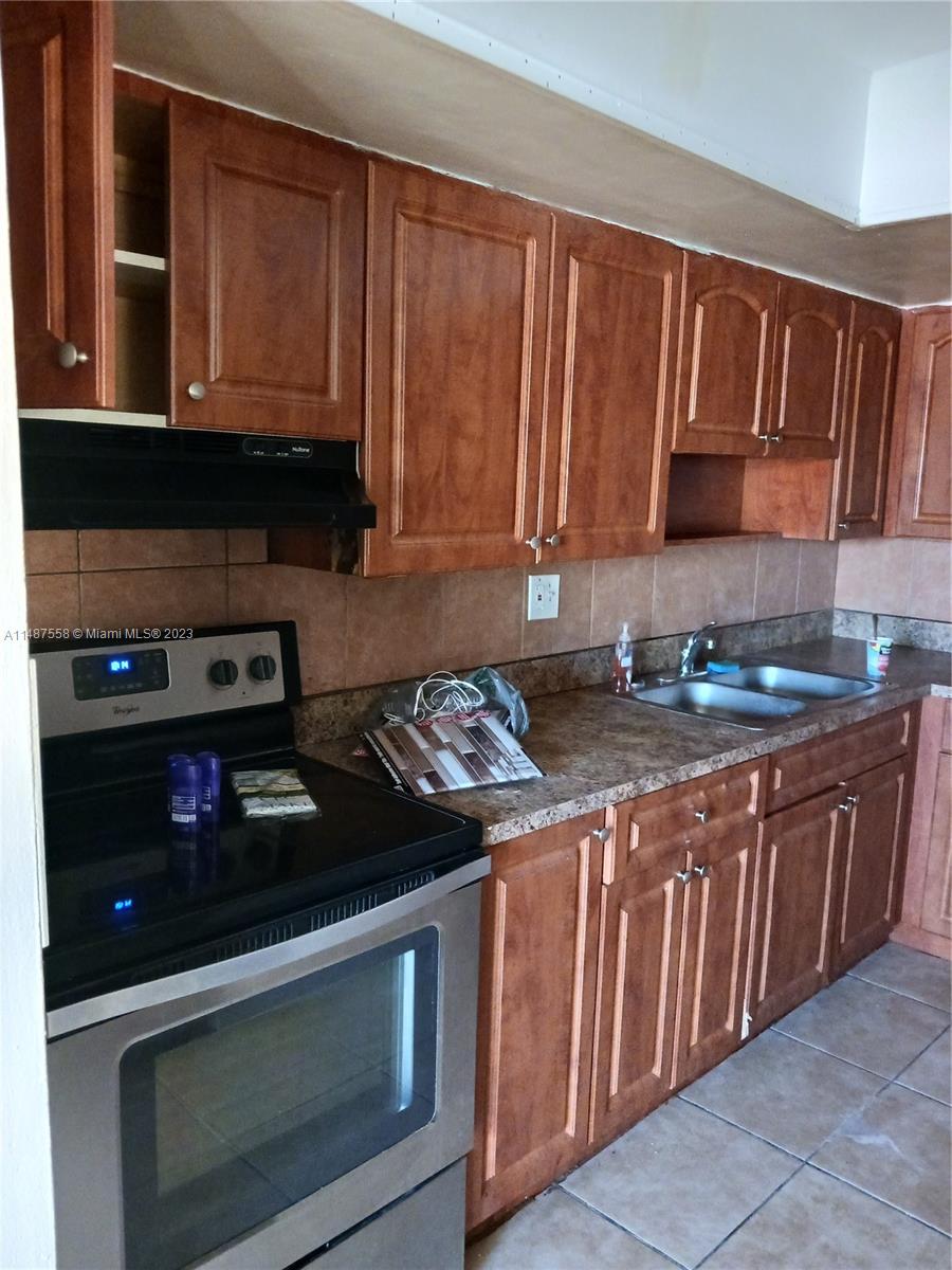 a kitchen with granite countertop stainless steel appliances a stove a sink dishwasher and cabinets with wooden floor