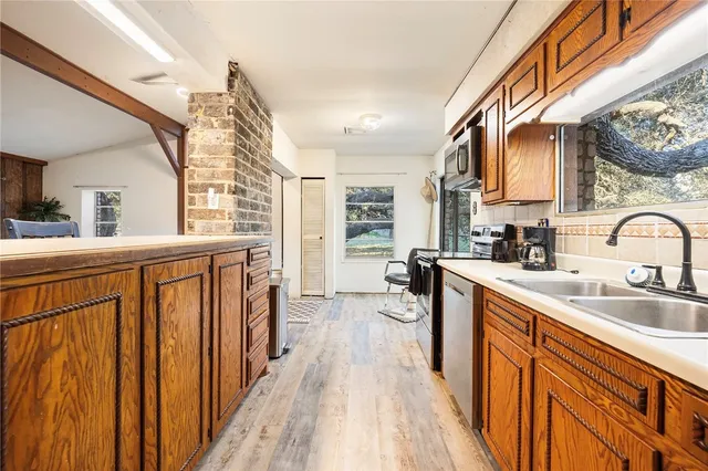 a kitchen with stainless steel appliances granite countertop a sink dishwasher stove and wooden cabinets