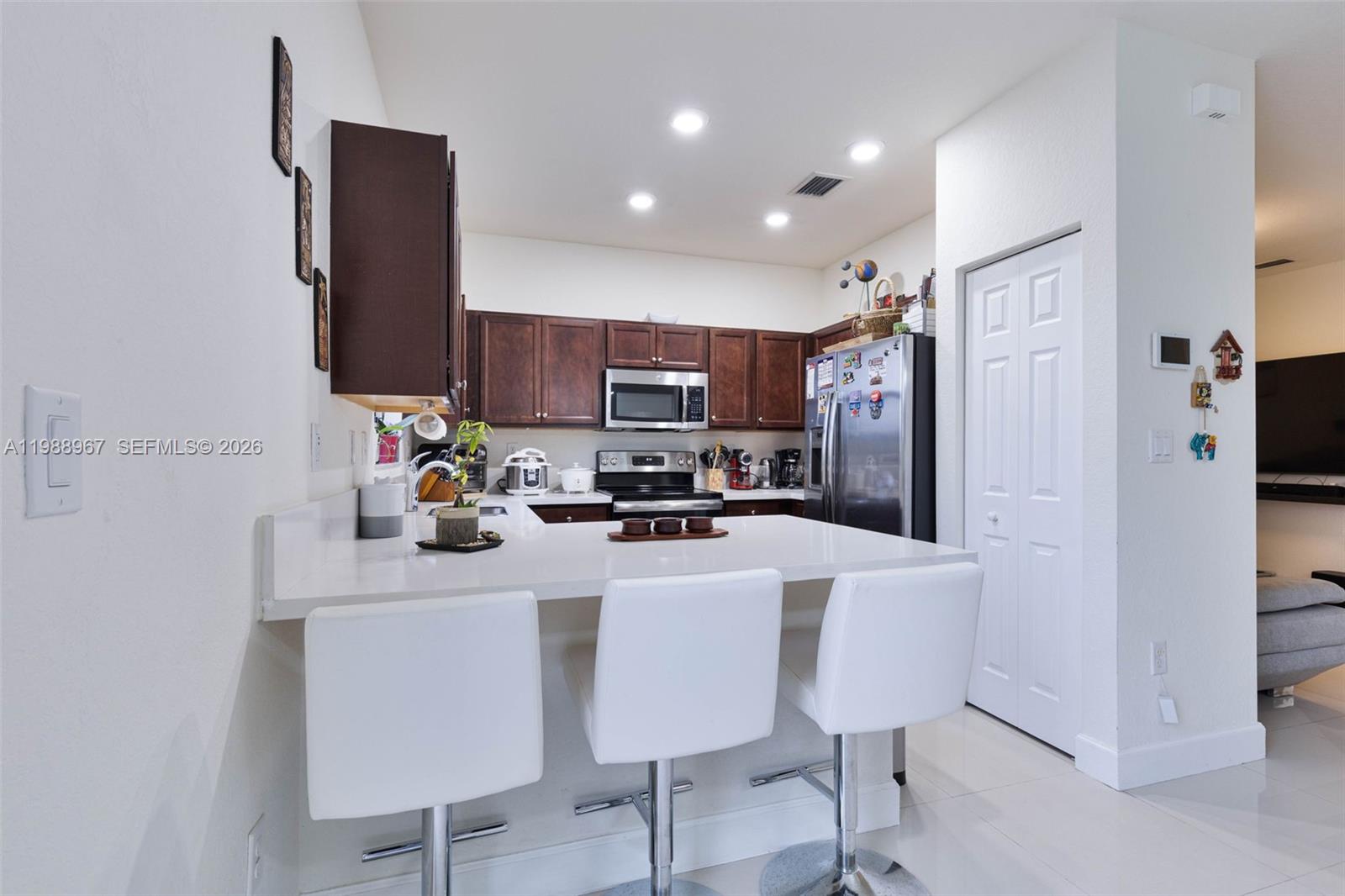 9015 Northwest 183rd Street Hialeah, FL 33018 - Photo 12 of 45 a kitchen with stainless steel appliances a refrigerator sink and wooden cabinets