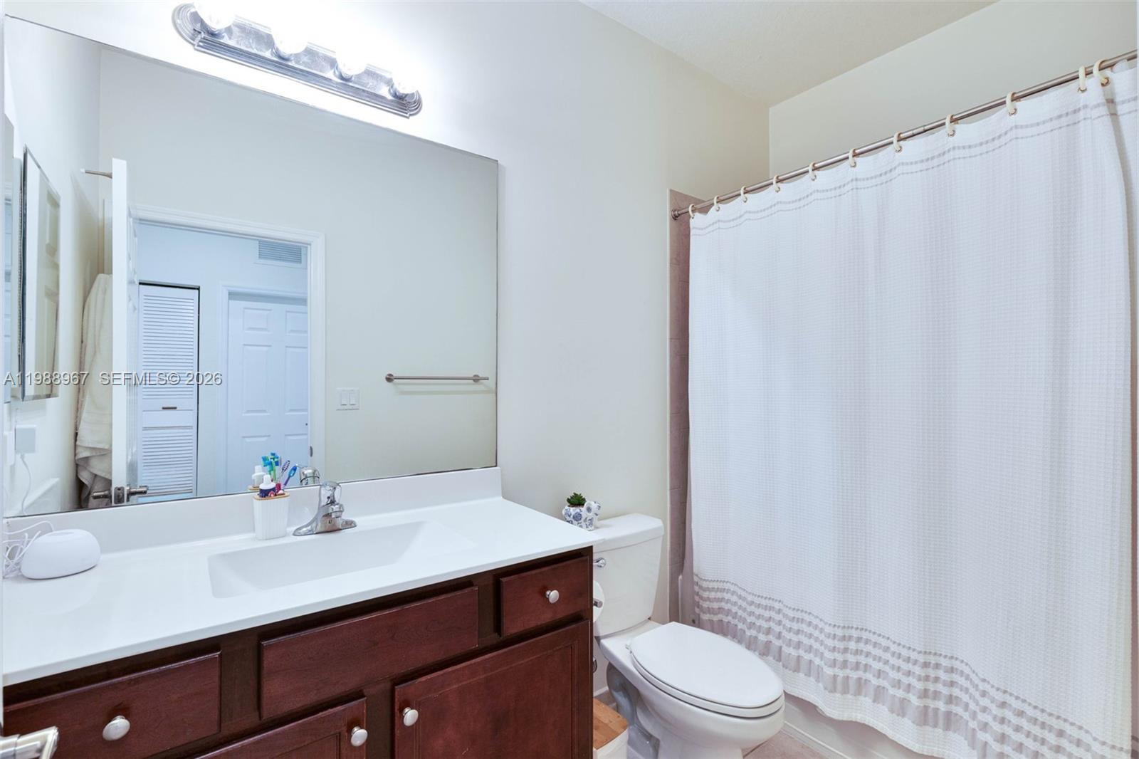 9015 Northwest 183rd Street Hialeah, FL 33018 - Photo 22 of 45 a bathroom with a sink a toilet and shower curtain