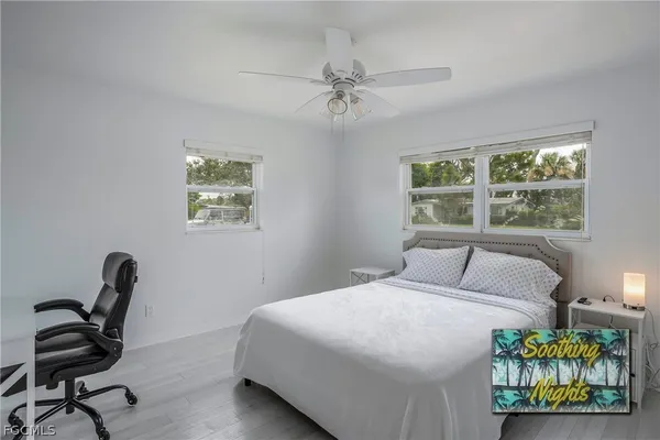a bedroom with a bed a desk and chair with window