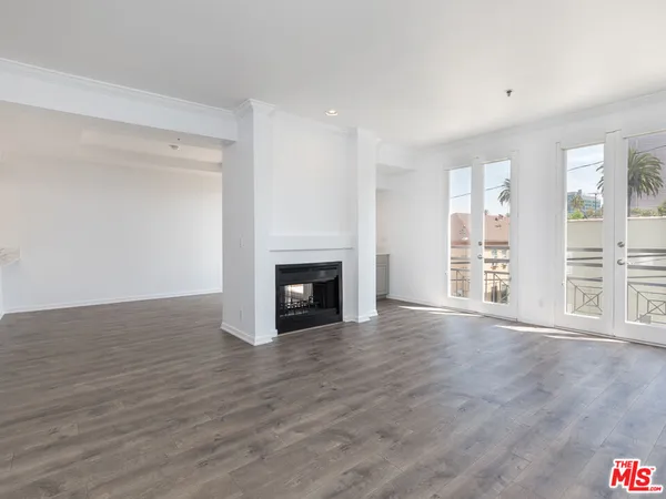 a view of an empty room with wooden floor and a fireplace