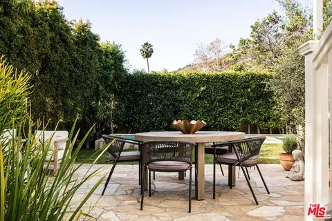 a view of patio with table and chairs and potted plants with wooden floor and fence