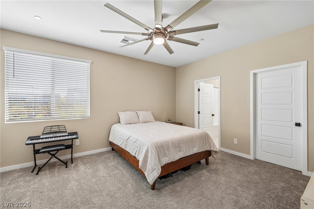 194 Viento Ridge Street Henderson, NV 89012 - Photo 45 of 72 An inviting bedroom space features plush carpeting and a large window offering natural light.