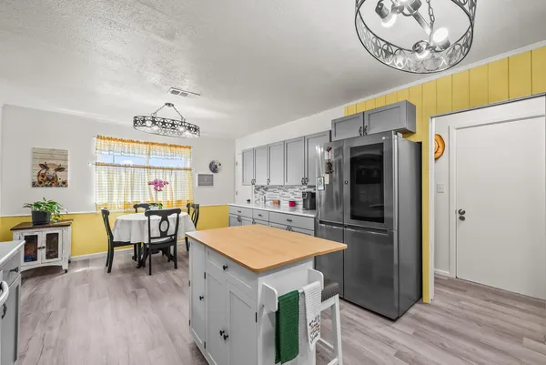 a kitchen with a refrigerator a stove a dining table and chairs with wooden floor