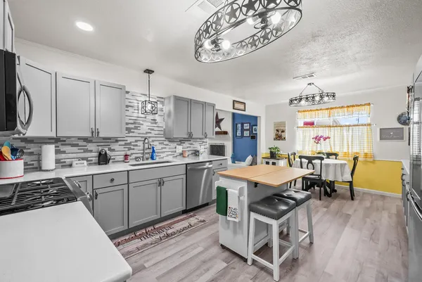 a kitchen with stainless steel appliances a table chairs and a refrigerator
