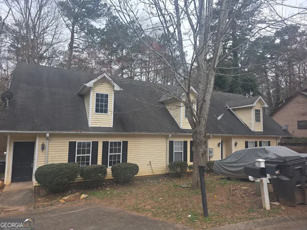 a front view of a house with yard and parking