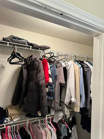 a view of walk in closet with clothes and shoes