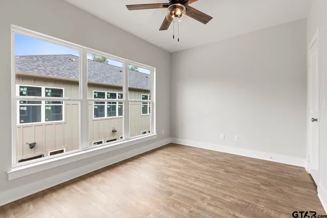 a view of an empty room with a window and chandelier fan