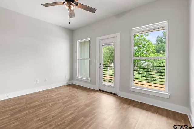 a view of an empty room with wooden floor and a window