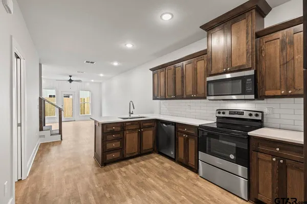 a large kitchen with stainless steel appliances wooden cabinets and a stove top oven