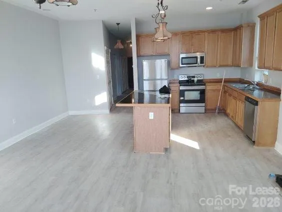 an empty room with wooden floor chandelier and windows