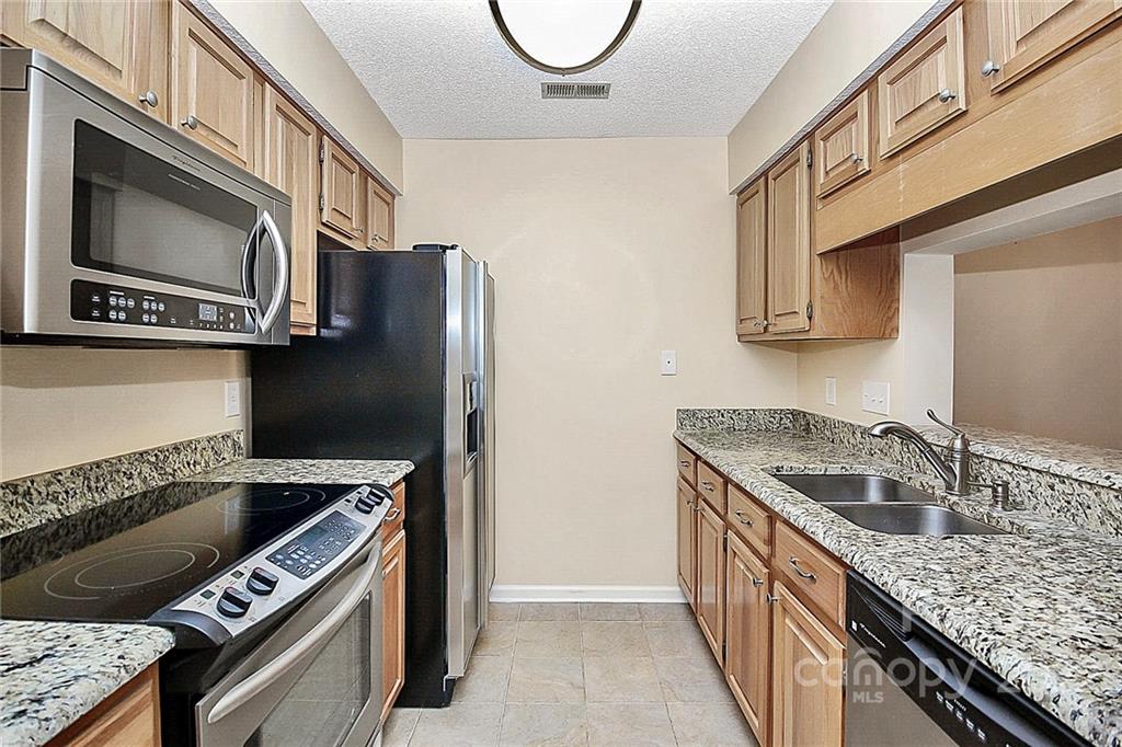 5003 Sharon Road, Unit N Charlotte, NC 28210 - Photo 3 of 11 a kitchen with stainless steel appliances granite countertop a stove a sink and a microwave