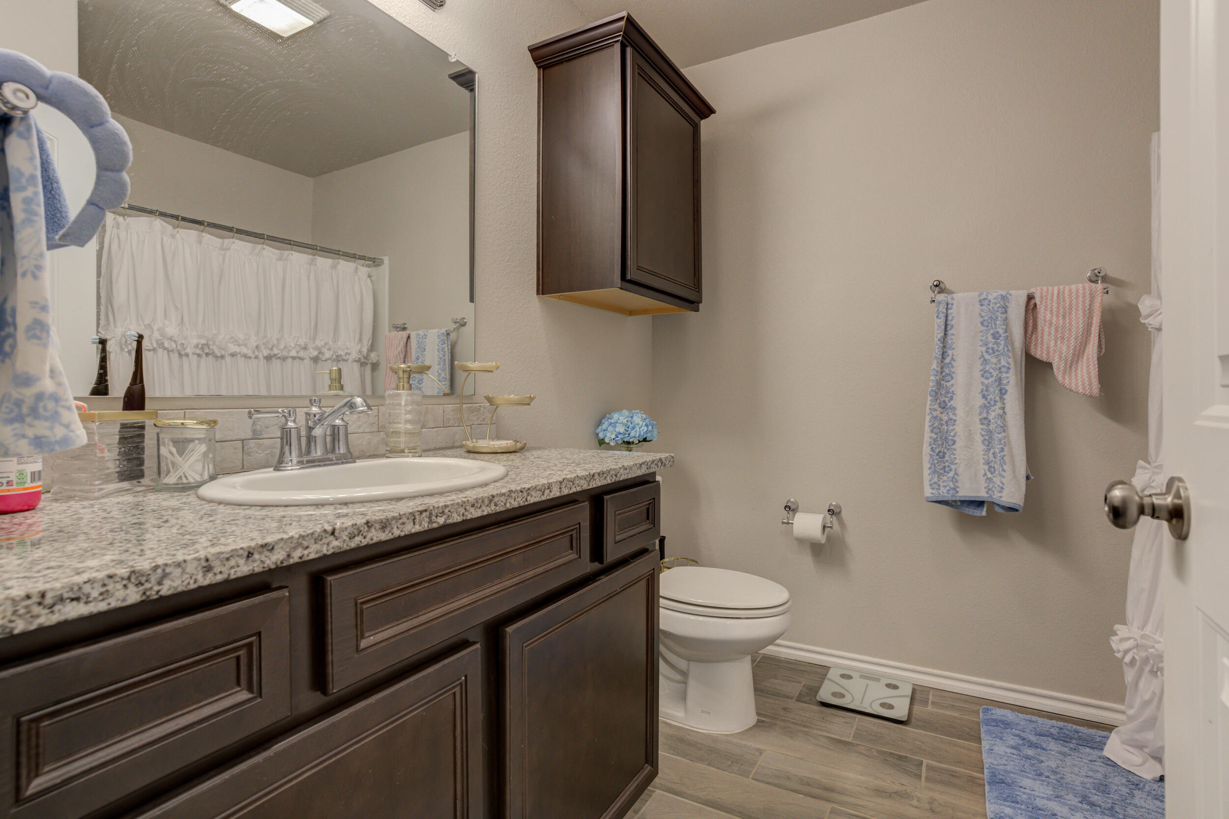 6818 40th Street Lubbock, TX 79407 - Photo 36 of 43 a bathroom with a granite countertop sink a toilet and a mirror