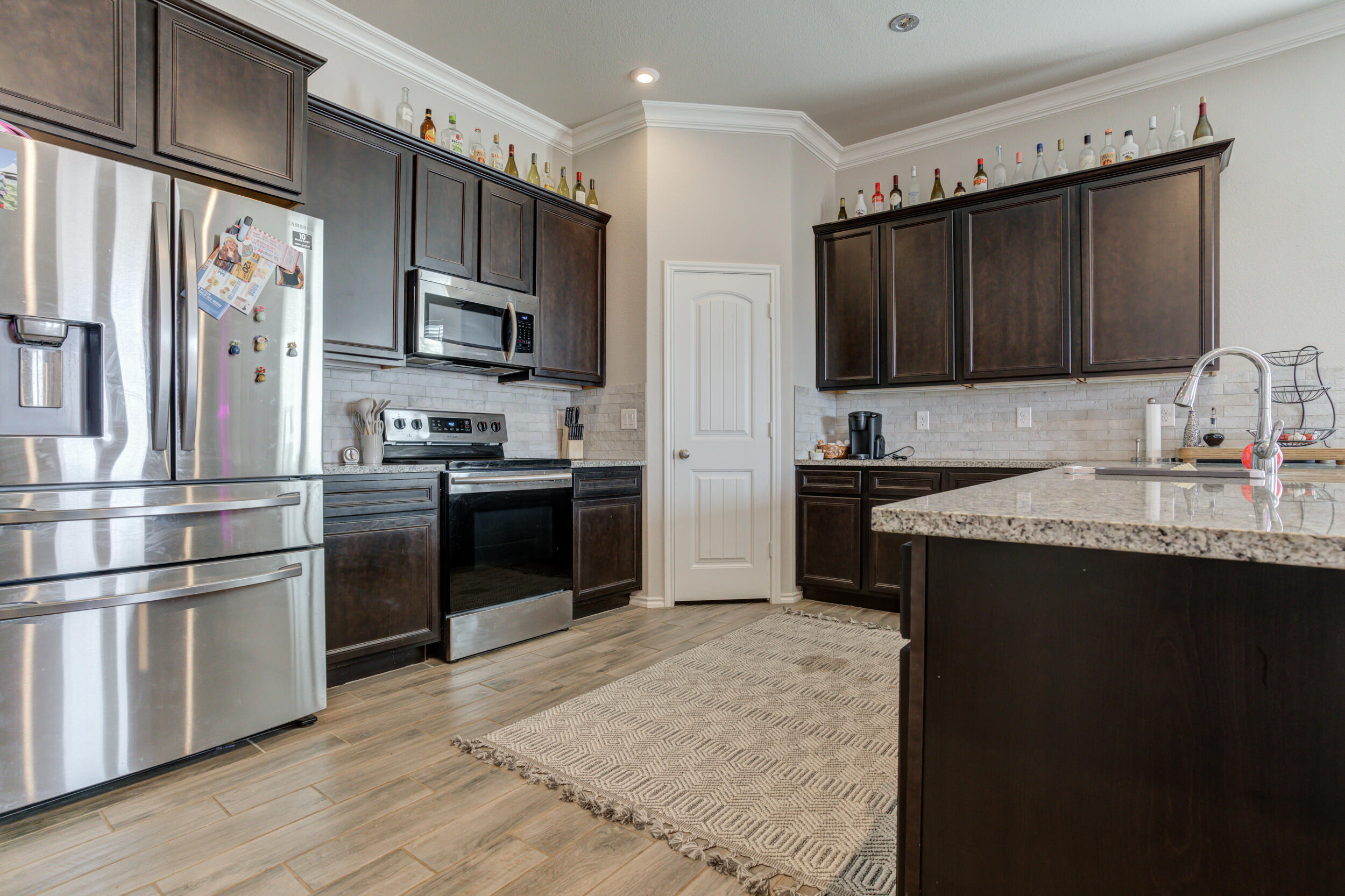 6818 40th Street Lubbock, TX 79407 - Photo 6 of 43 a kitchen with granite countertop a refrigerator stove and microwave