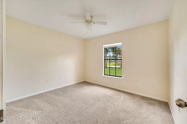 an empty room with a window and a ceiling fan