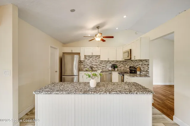 a kitchen with kitchen island granite countertop cabinets and refrigerator