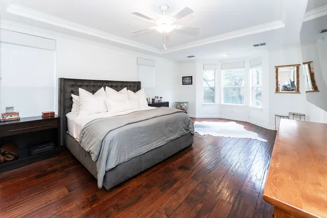 a large bedroom with wooden floor and window