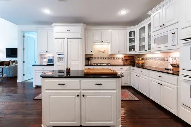 a kitchen with granite countertop white cabinets and white appliances