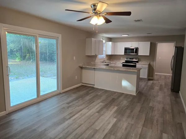 a kitchen with stainless steel appliances a stove a refrigerator a sink a microwave oven with wooden floor and cabinets