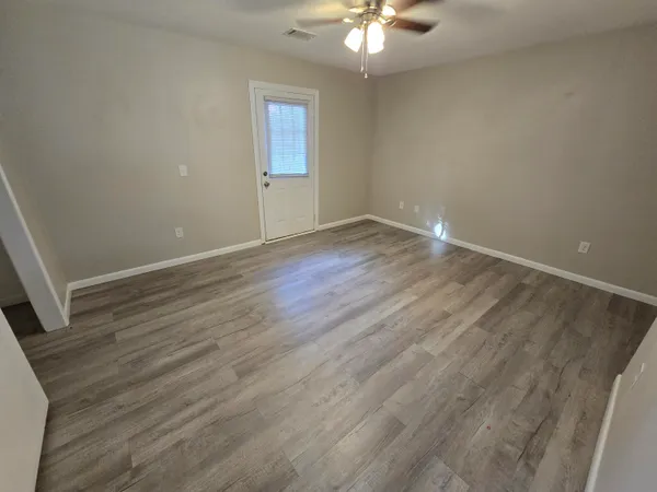 an empty room with wooden floor and fan