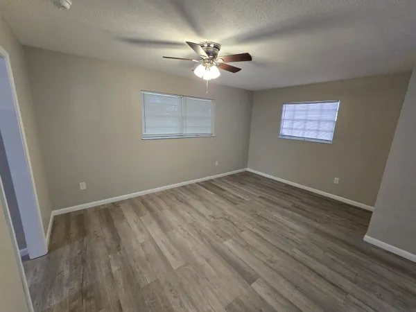 a view of an empty room with a window and wooden floor