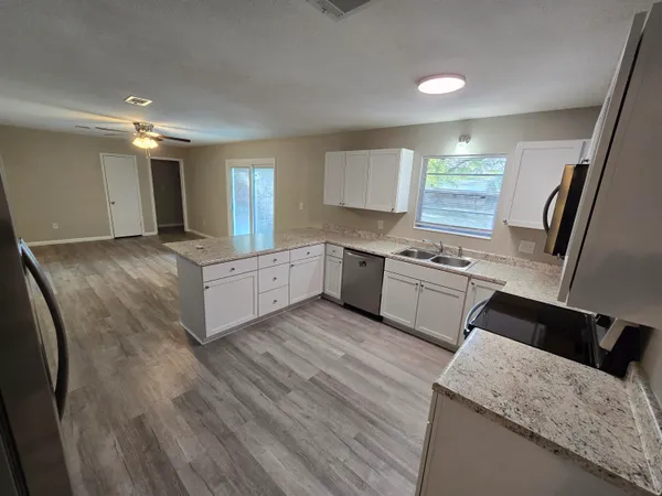 a kitchen with granite countertop a sink a stove cabinets and wooden floor