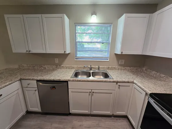 a kitchen with white cabinets appliances a sink and a window
