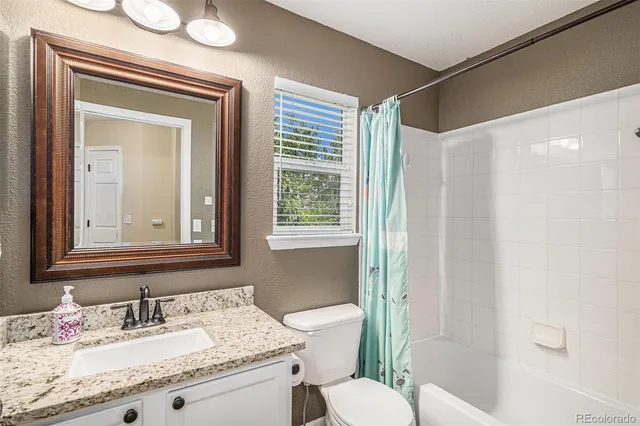 a bathroom with a granite countertop sink toilet a mirror and shower