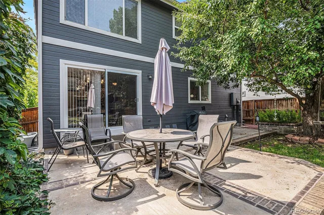 a view of a patio with table and chairs potted plants and large tree