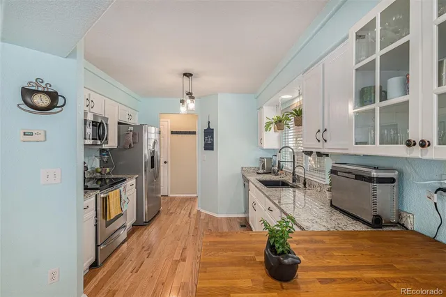 a kitchen with stainless steel appliances granite countertop a refrigerator a stove and a wooden floors