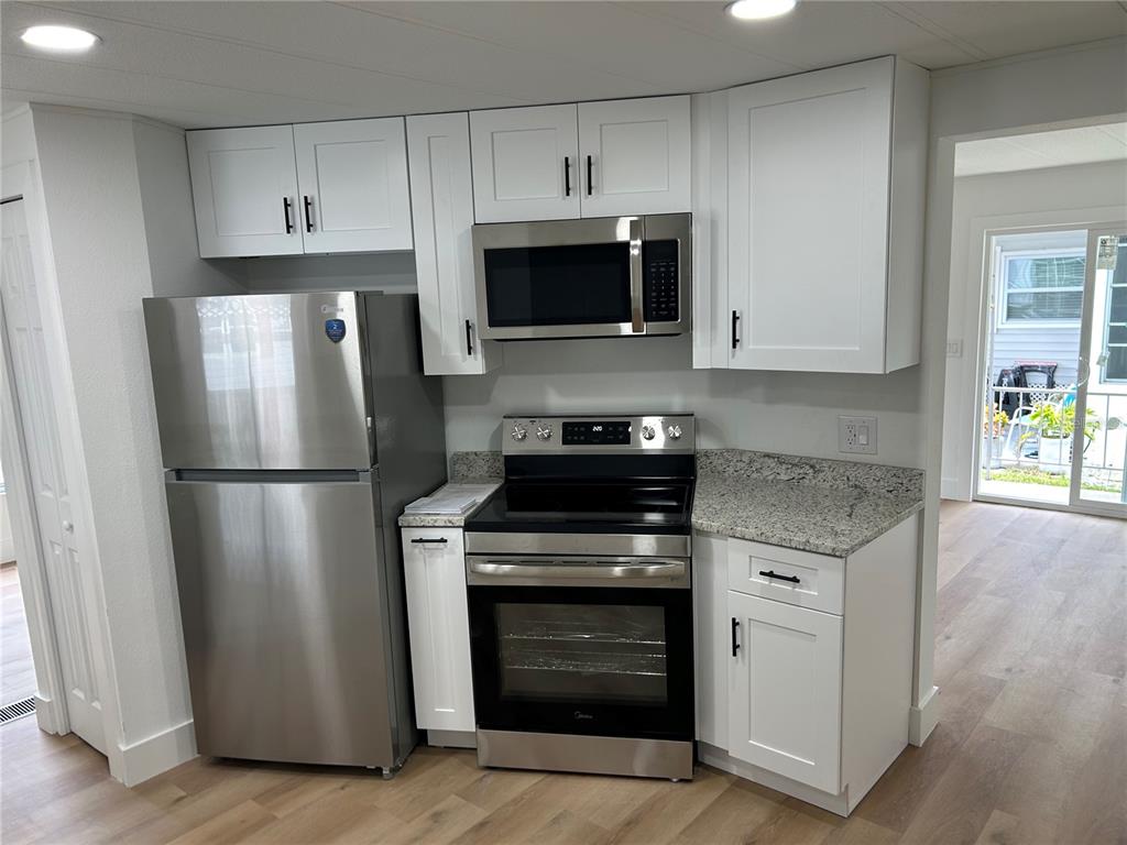 4443 Tucker Square New Port Richey, FL 34652 - Photo 11 of 24 a kitchen with stainless steel appliances granite countertop a stove a refrigerator and a microwave
