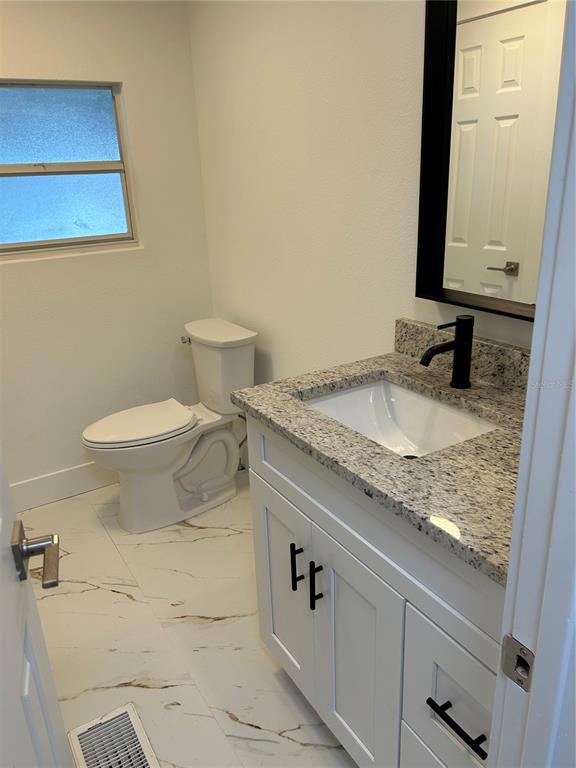 4443 Tucker Square New Port Richey, FL 34652 - Photo 18 of 24 a bathroom with a granite countertop sink and a toilet