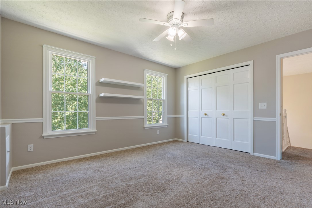 3960 Bramshaw Road Northwest Canton, OH 44718 - Photo 27 of 33 Unfurnished bedroom featuring multiple windows, ceiling fan, carpet floors, and a textured ceiling