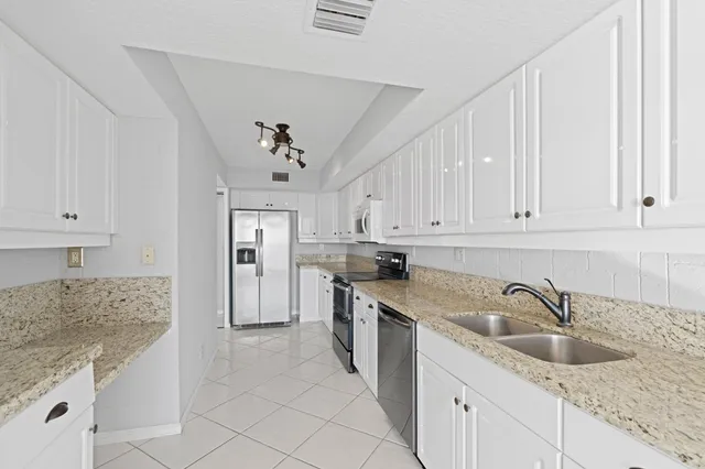 a kitchen with granite countertop a sink and white cabinets