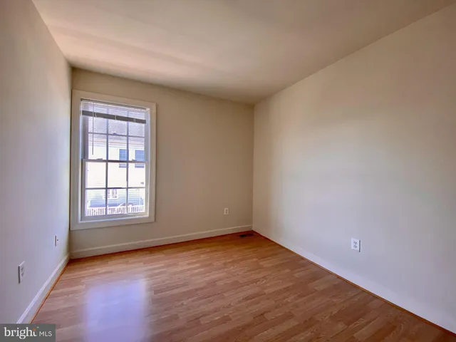 an empty room with wooden floor and window