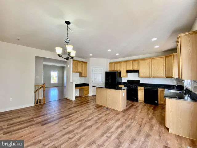 a view of a kitchen with kitchen island a refrigerator a stove a sink dishwasher a dining table and chairs with wooden floor