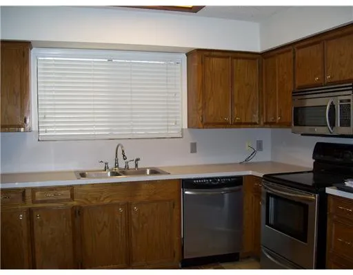 a kitchen with a sink a stove a microwave cabinets and a window