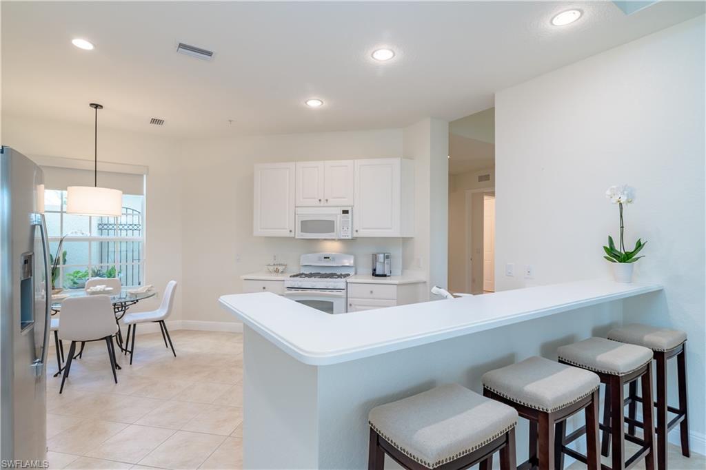 9271 Museo Circle, Unit 102 Naples, FL 34114 - Photo 9 of 35 a kitchen with a table chairs sink and cabinets