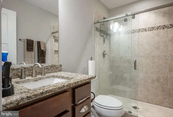 a bathroom with a granite countertop sink toilet a mirror and shower