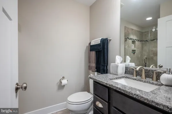 a bathroom with a granite countertop sink a toilet and a mirror