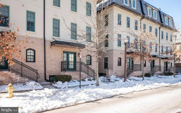 a view of a white house with large windows next to a road