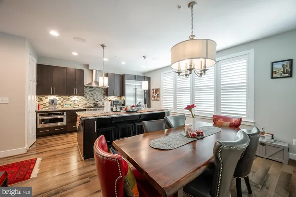 a kitchen with granite countertop kitchen island stainless steel appliances a dining table and chairs a stove with wooden floor