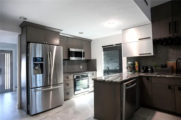 a kitchen with granite countertop a refrigerator stove and microwave