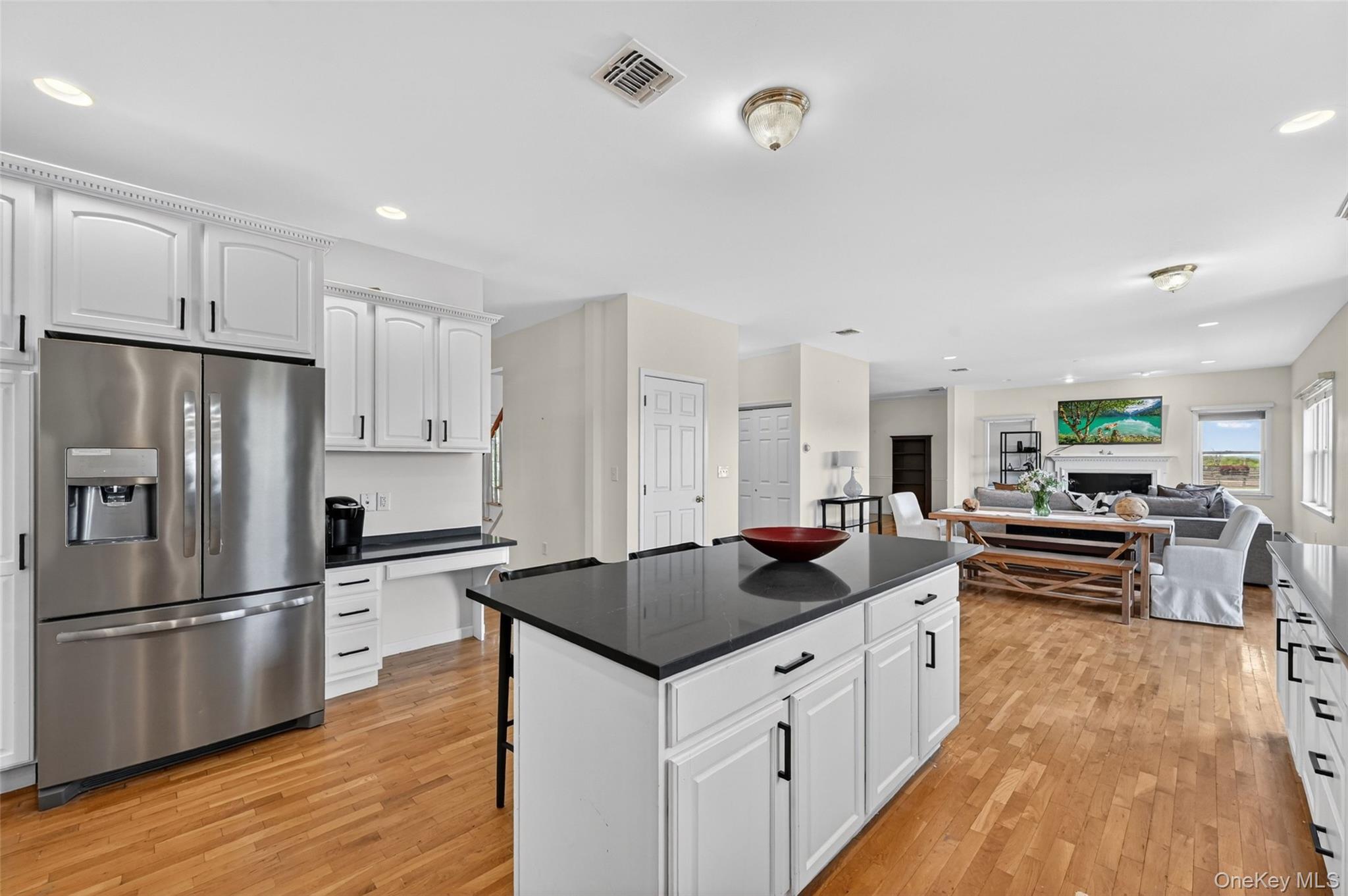 19 Bull Mine Road Chester, NY 10918 - Photo 15 of 42 Open-concept kitchen featuring an island with a dark Granite countertop, white cabinetry with black hardware, stainless steel refrigerator, and wood-finish flooring